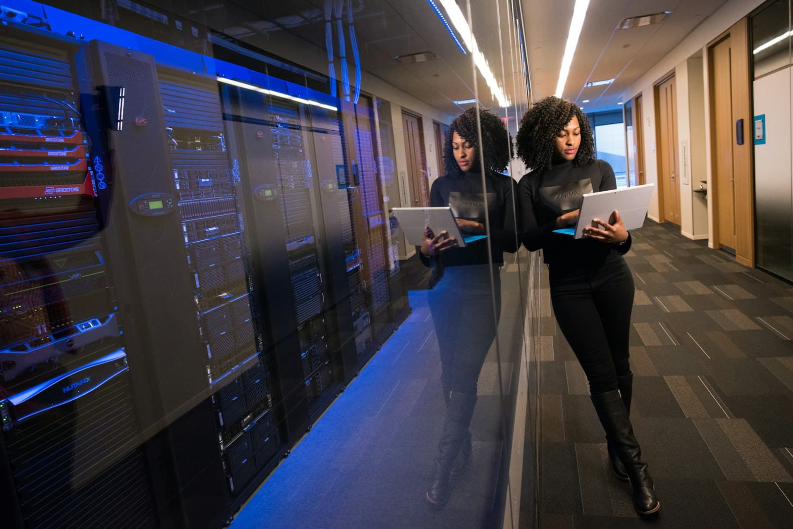 An engineer holding a laptop in a corridor of server racks