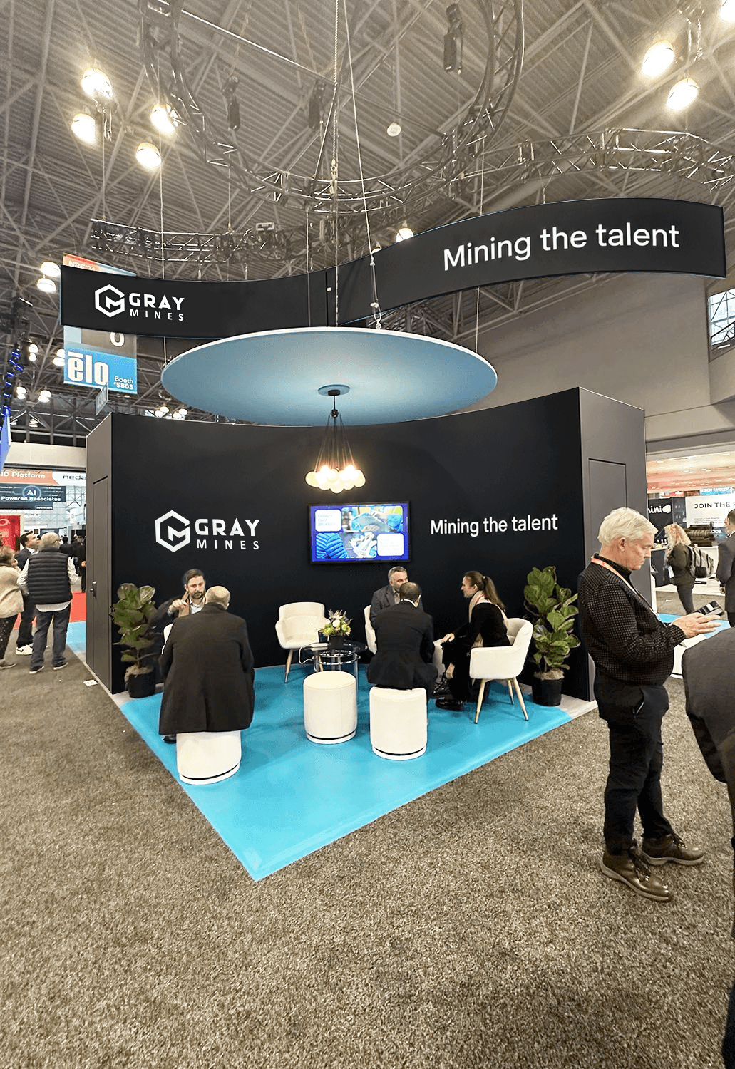 The Gray Mines stand on a busy expo floor, its curved sign reading Mining the talent