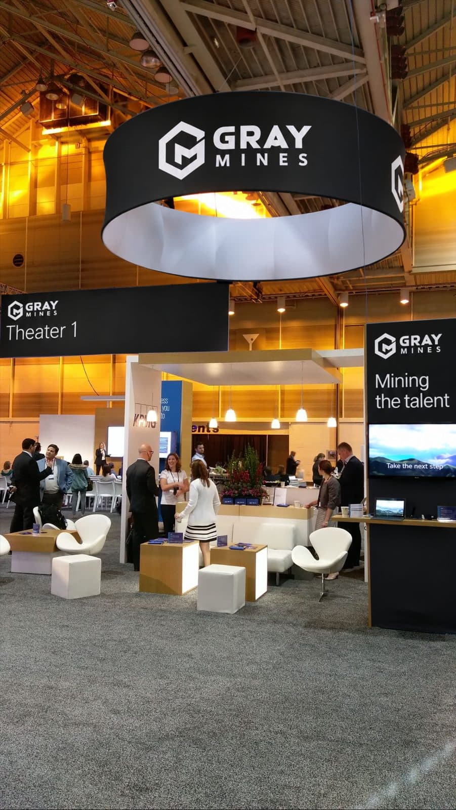 The Gray Mines stand at an exhibition, a ring-shaped sign above a lounge with white seats