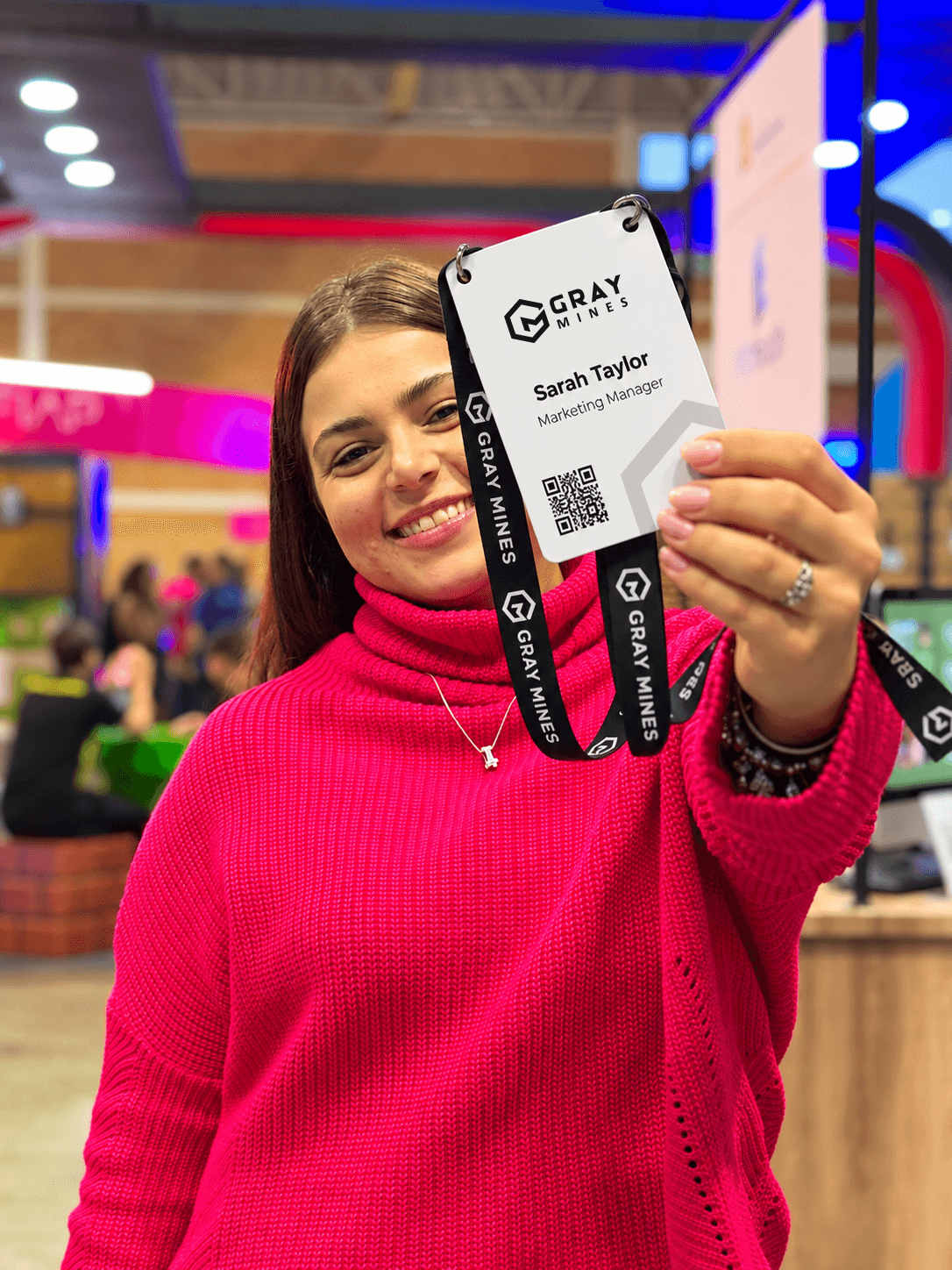A member of the Gray Mines team smiling and holding up her name badge on a Gray Mines lanyard