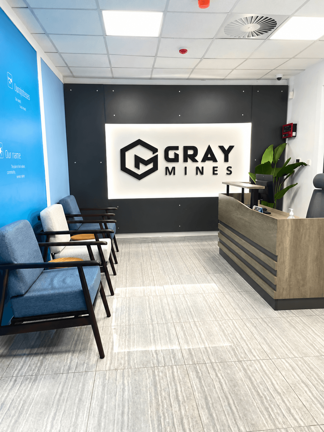 The Gray Mines reception, the logo on a dark wall behind the desk