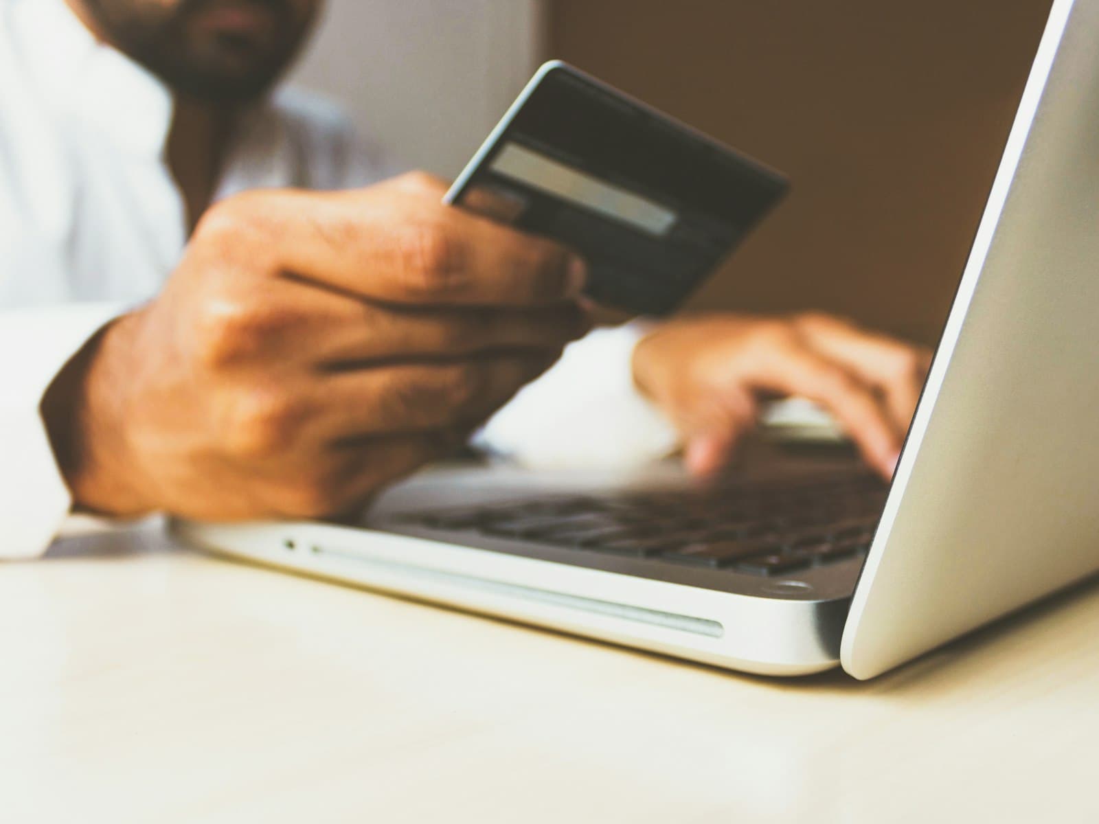 A shopper holding a bank card while buying on a laptop