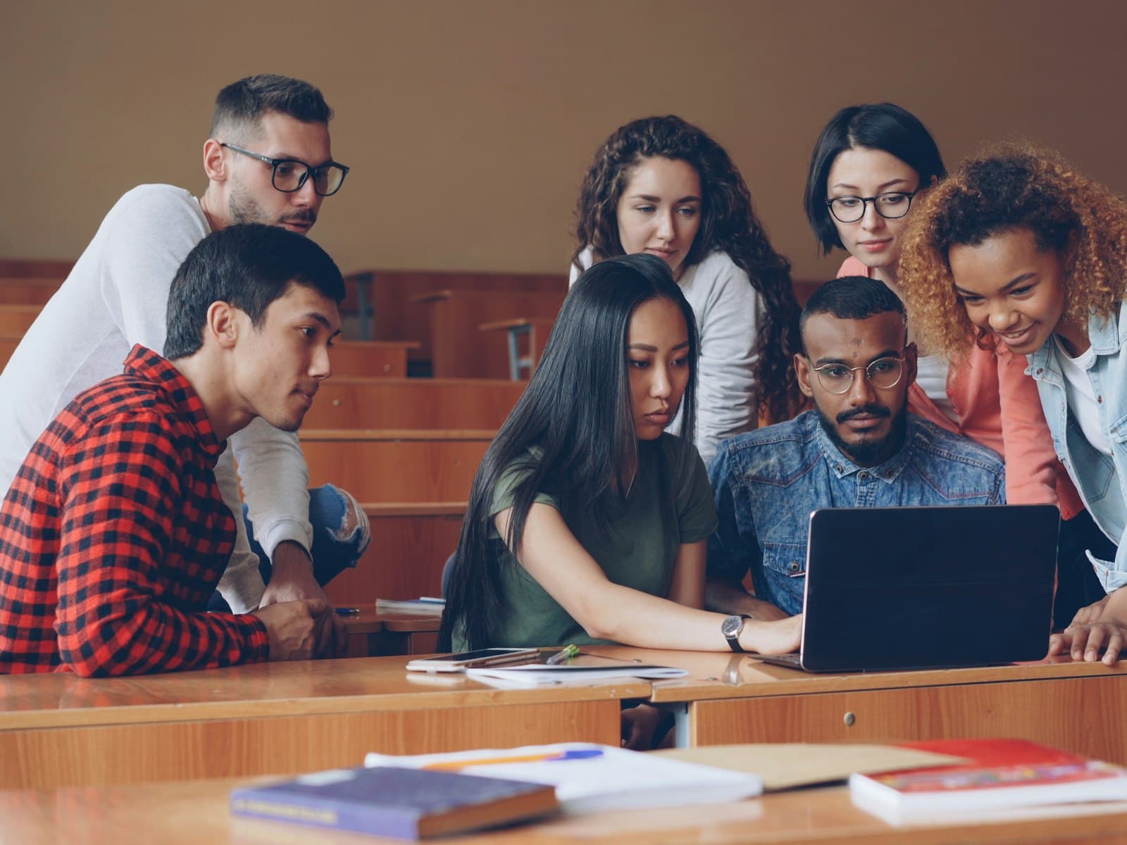 Students gathered around a laptop in a lecture hall