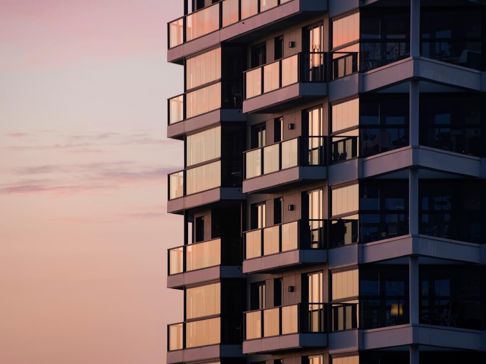 An apartment building with glass balconies at dusk
