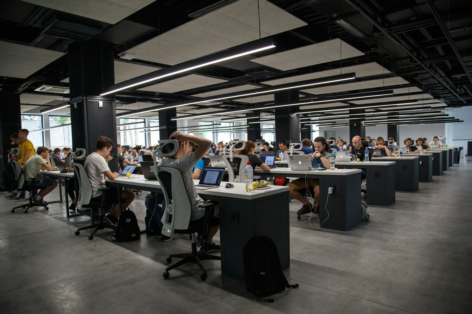 A busy open-plan office with long rows of people working at their desks