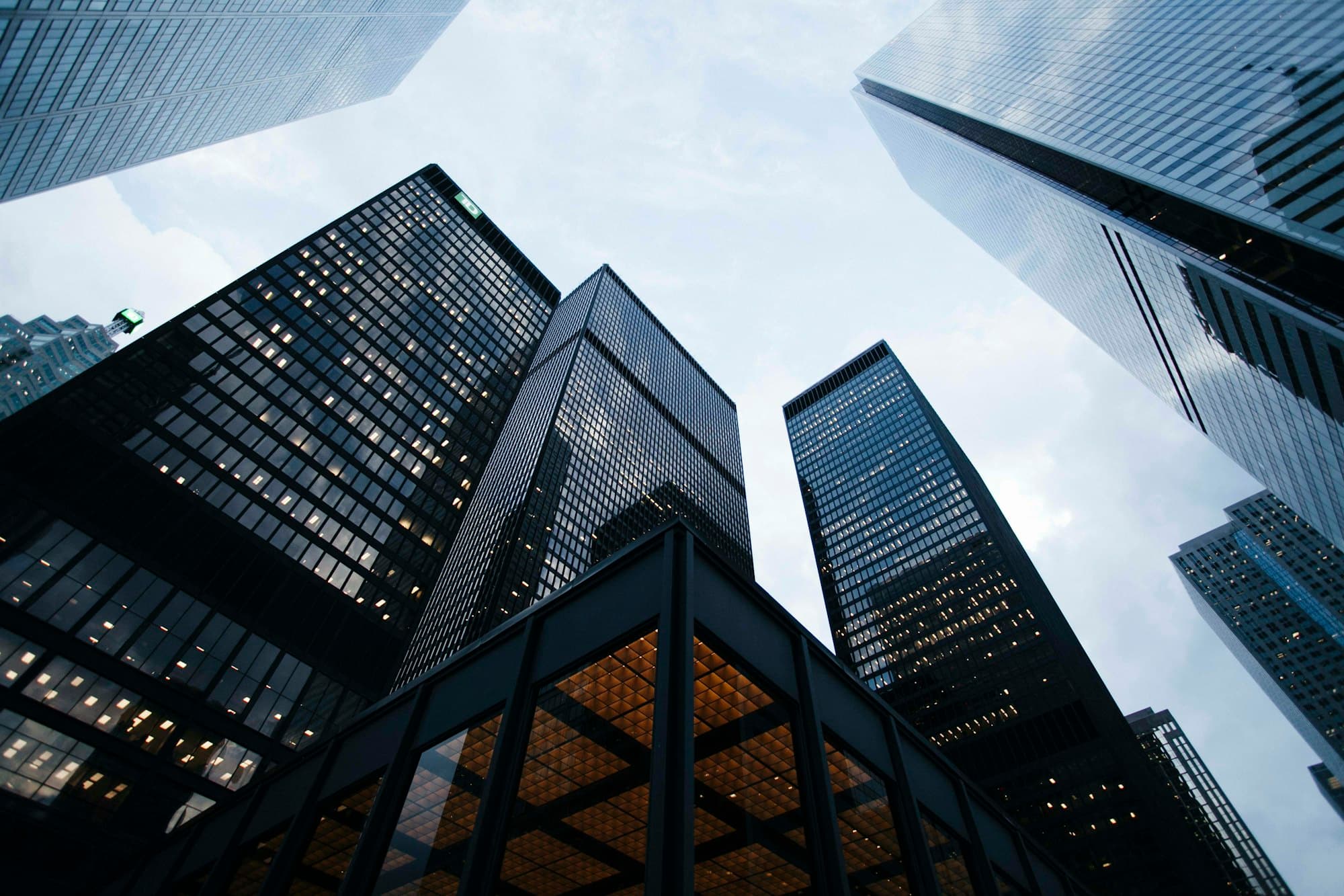 Glass office towers seen from street level against a pale sky